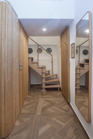 A wooden staircase with a herringbone floor pattern leading to a landing with decorative plates. - Exclusive Syntagma & Plaka 2BD Townhouse (Athina)