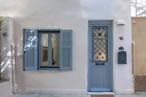 Eine Gebäudefassade mit einer geschlossenen Tür, einem Fenster mit Rollläden und einem Briefkasten.