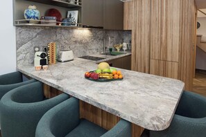 A modern kitchen with a marble countertop, a fruit bowl, and a vintage radio. - Exclusive Syntagma & Plaka 2BD Townhouse (Athina)
