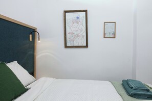 A bedroom with a bed, a wall-mounted lamp, and two framed artworks. - Exclusive Syntagma & Plaka 2BD Townhouse (Athina)