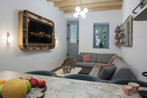 Ein Wohnzimmer mit Fernseher, einer Couch, einem Couchtisch und einer Obstschale.
