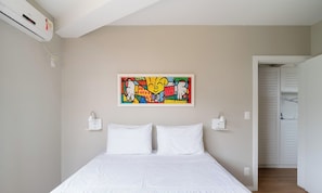 Quarto com cama, pintura abstrata colorida e unidade de ar condicionado branca.
