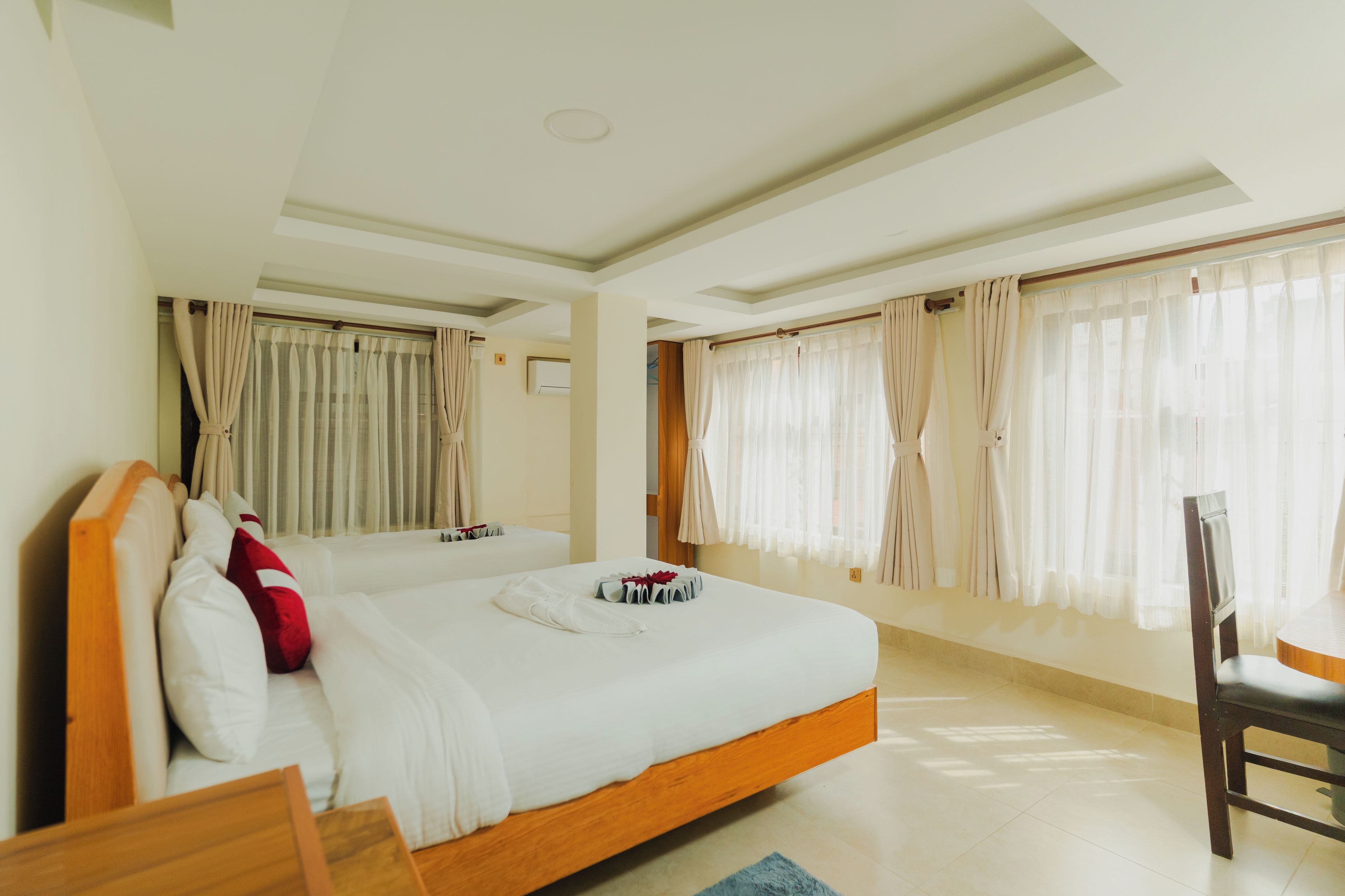 Een hotelkamer met twee bedden, een houten hoofdeinde, een tafeltje en een stoel.