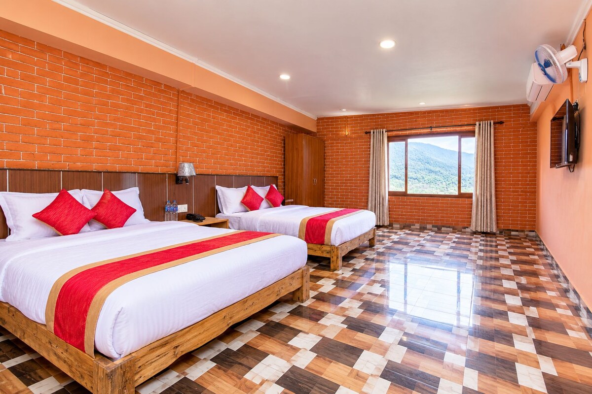A hotel room with two beds, a brick wall, a large window, and a tiled floor.