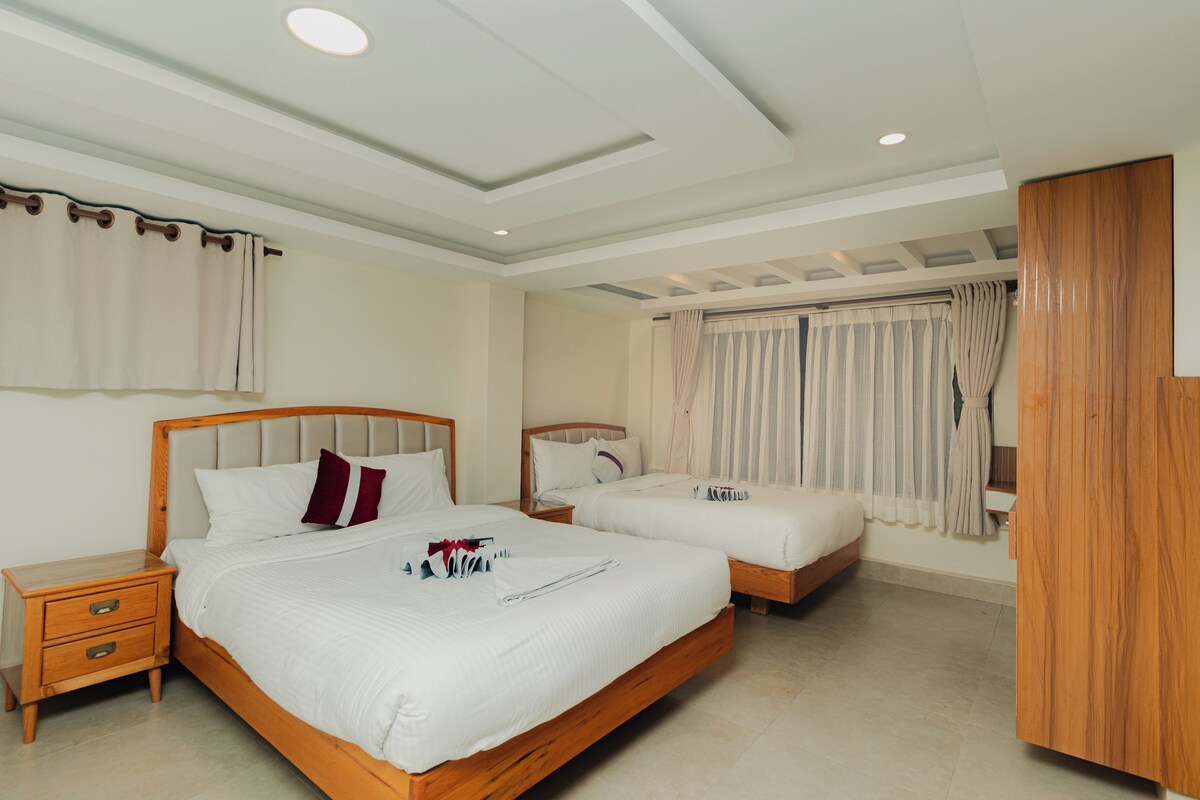 A hotel room with two beds, a wooden headboard, a nightstand, and a wardrobe.
