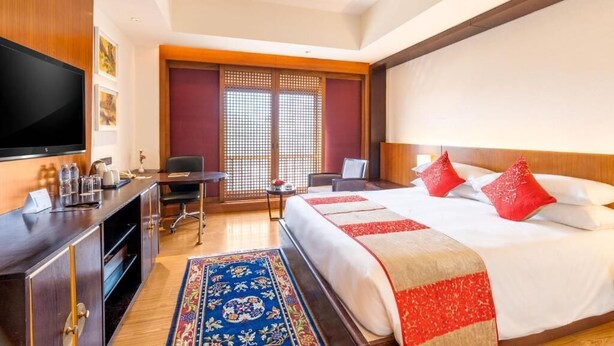 Une chambre d’hôtel avec un lit, un bureau, une télévision et une fenêtre donnant sur un paysage agréable.