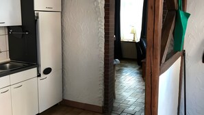 Una cocina estrecha con armarios blancos, una encimera negra y una pared de ladrillo.