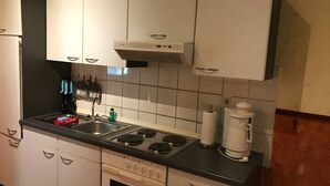 Keittiössä on valkoiset kaapit, musta työtaso, sisäänrakennettu uuni ja kahvinkeitin.