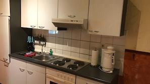 A kitchen with white cabinets, a black countertop, a built-in oven, and a coffee maker. - Holiday Apartment '4-Juist' with Wi-Fi (Dornum)