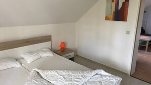 A bedroom with a bed, a nightstand, and a lamp. - Holiday Apartment "Spiekeroog" – 1 Bedroom (Dornum)