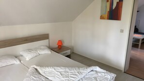 A bedroom with a bed, a nightstand, and a lamp. - Holiday Apartment "Spiekeroog" – 1 Bedroom (Dornum)