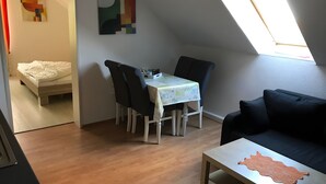 A compact living space with a dining area, a sofa, and a small table with a placemat. - Holiday Apartment "Spiekeroog" – 1 Bedroom (Dornum)