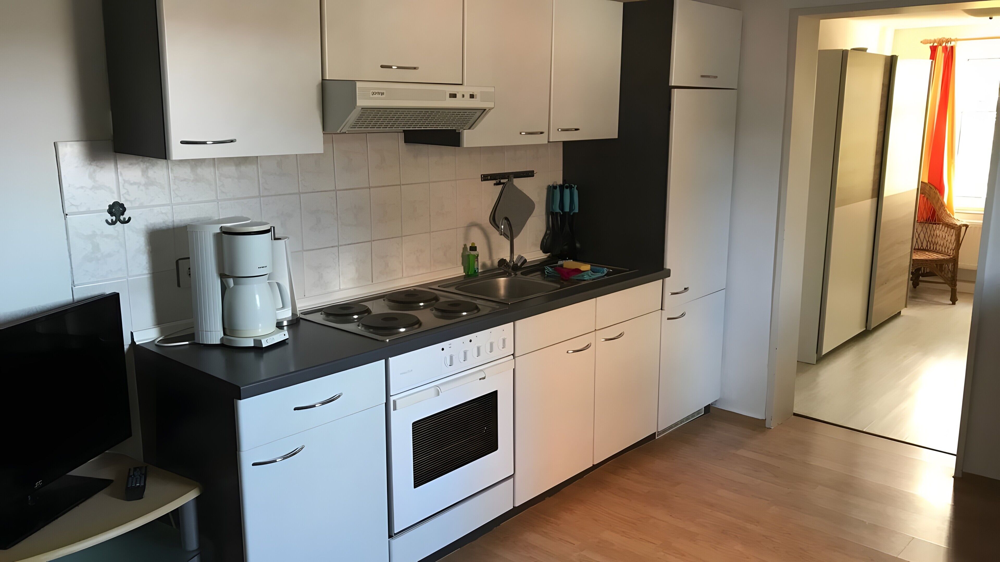 Una cocina moderna con armarios blancos, una estufa y una cafetera.