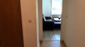 Ein Flur, der in einen Wohnbereich mit einer Couch und einem Tisch führt.