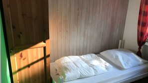 Ein Einzelbett mit weißer Bettwäsche in einem Zimmer mit Holzwandverkleidung.