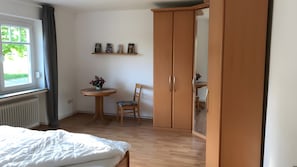 Ein Schlafzimmer mit einem Bett, einem Holzschrank, einem kleinen runden Tisch mit Stuhl und einem Bücherregal.