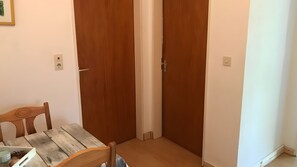 Ein Zimmer mit einem Holztisch, Stühlen, zwei Holztüren und einem Lichtschalter an der Wand.