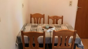 Ein Esstisch mit vier Holzhöcken, ein weißer Tablett mit einer Kerze und eine kleine Pflanze.