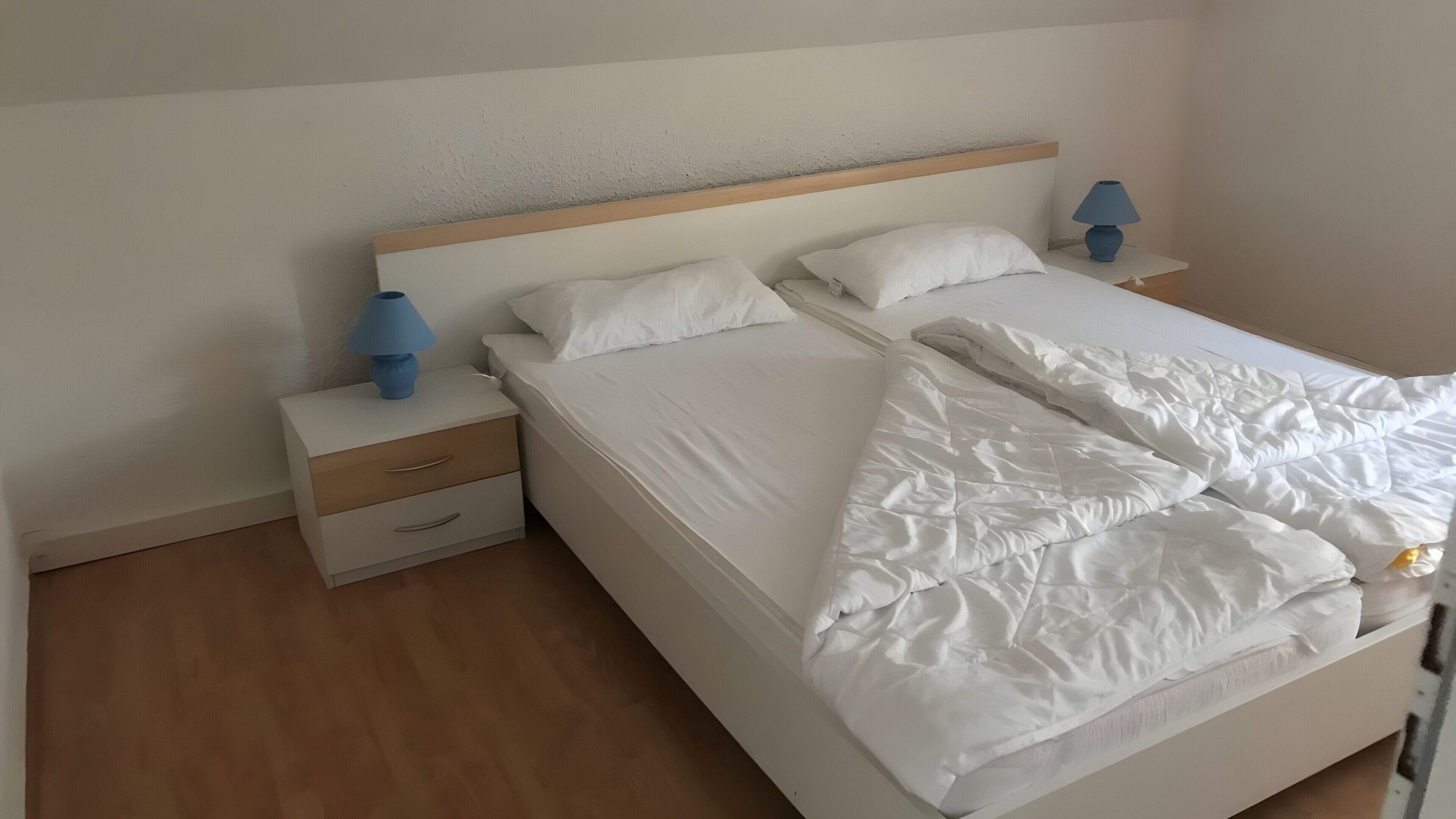 Quarto de hotel com uma cama, duas mesas de cabeceira e um criado-mudo.
