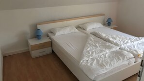 A hotel room with a bed, two bedside tables, and a nightstand. - Apartment "Baltrum" – 1 Bedroom (Dornum)
