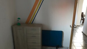 Ein Zimmer mit einem Holzkoffer, einer blauen Matratze und einer gestreiften Wand.