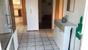 A kitchen with a refrigerator, a sink, and cabinets. There is a door leading to another room. - Apartment Borkum – 3 Bedrooms (Dornum)