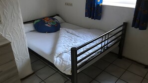A single bed with a metal frame, white bedding, and a blue pillow with a cartoon character. - Apartment Borkum – 3 Bedrooms (Dornum)