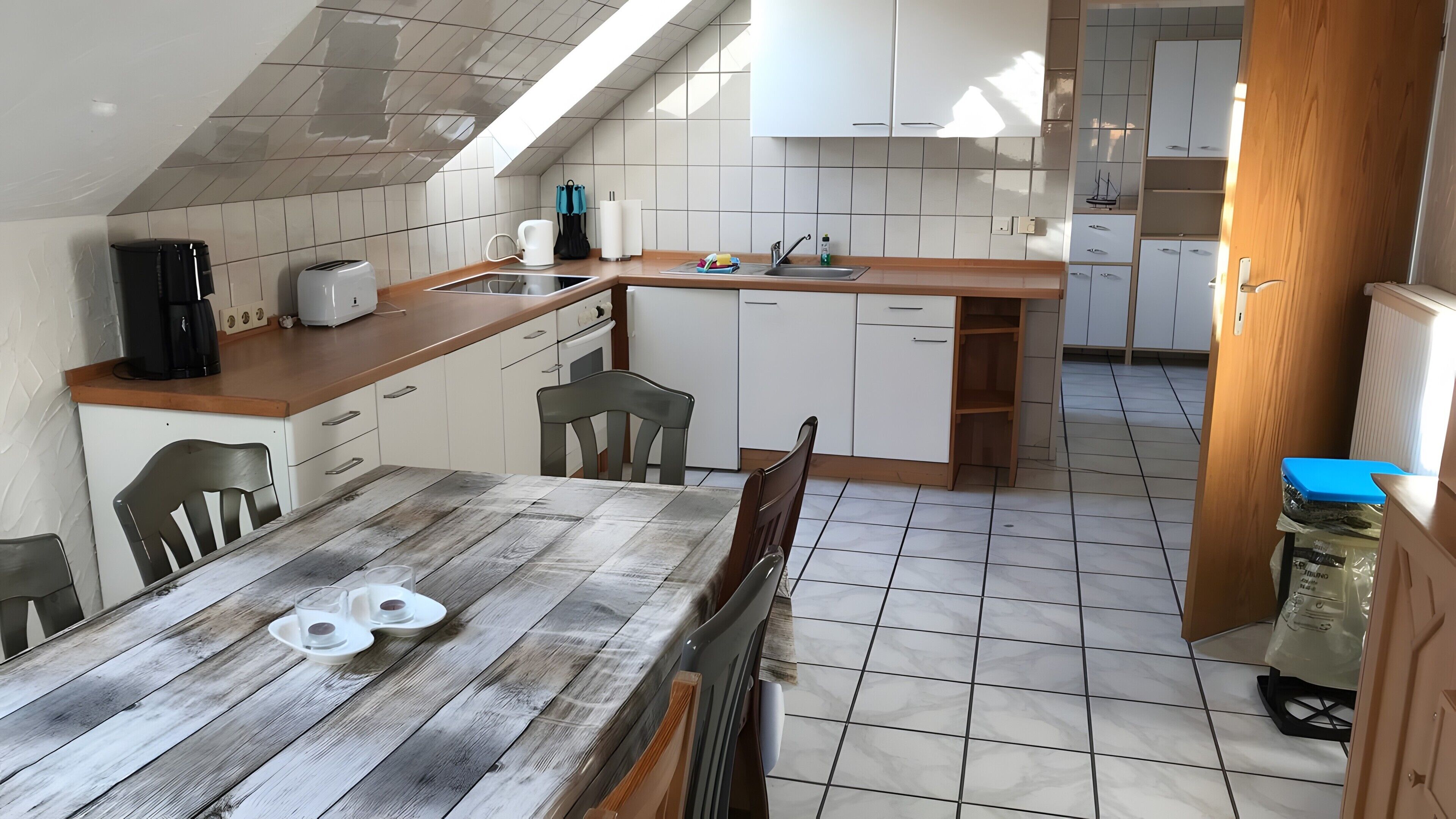 A kitchen with a wooden table, chairs, a coffee maker, and a toaster.