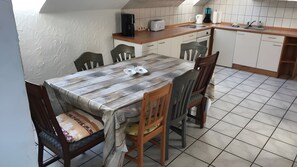 Ein Essbereich mit Holztisch, vier Stühlen und einer Küche im Hintergrund.