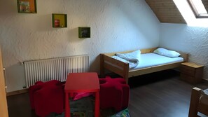 A small, cozy room with a bunk bed, a red table, and a radiator. - Apartment Borkum – 3 Bedrooms (Dornum)