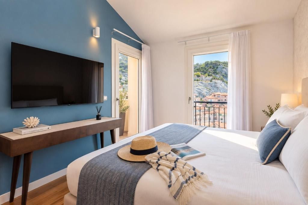 Ein Schlafzimmer mit Bett, Wandfernseher, Nachttisch und Blick ins Freie.