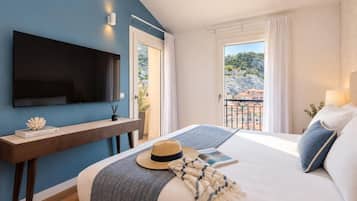 Ein Schlafzimmer mit Bett, Wandfernseher, Nachttisch und Blick ins Freie.