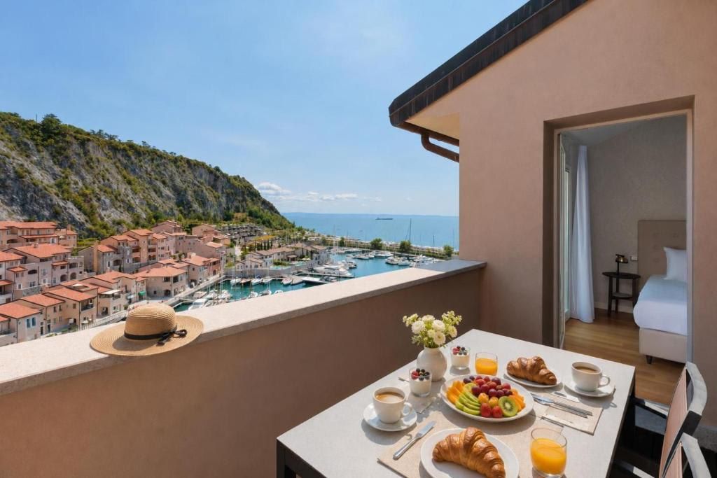 Ein Balkon mit Frühstückstisch, mit Blick auf einen Yachthafen und eine Küstenstadt.