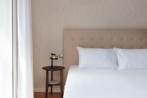 Ett hotellrum med en säng, ett nattduksbord, en lampa och en stol.