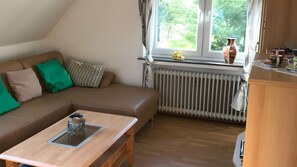 Un salon chaleureux avec un canapé marron, une table basse en bois et une fenêtre avec des rideaux.