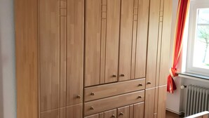 Un armario de madera con varios cajones y puertas, un radiador y una ventana con vistas a árboles.
