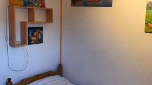 Una camera da letto con un letto in legno, uno scaffale con giochi per bambini e un quadro appeso al muro.