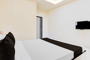 Una habitación de hotel con una cama, un televisor de pantalla plana en la pared y una puerta.