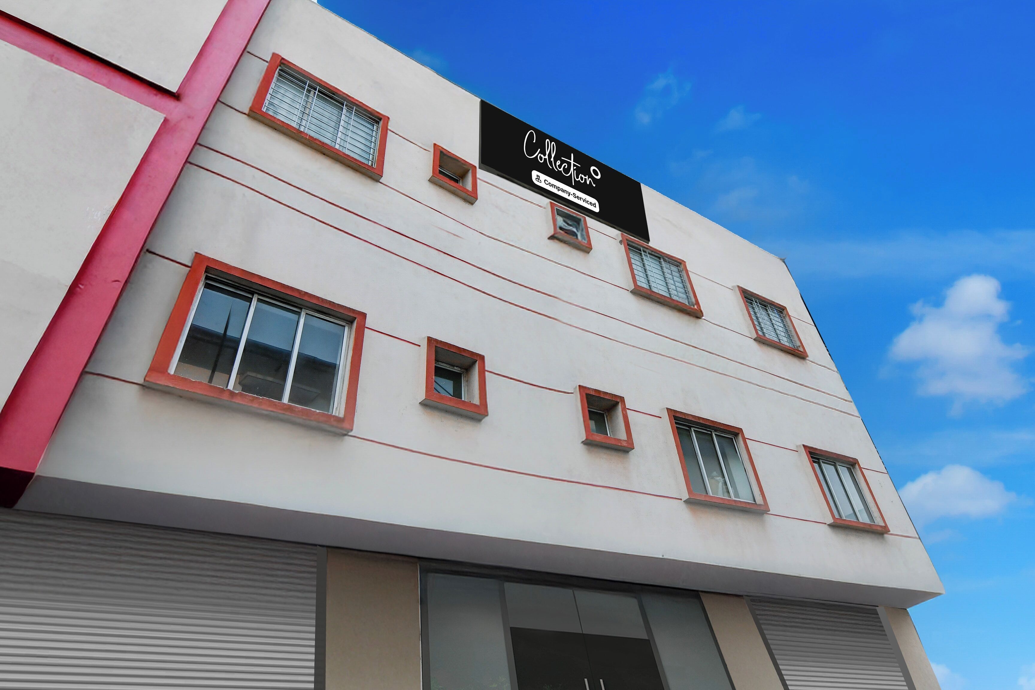 Um edifício com fachada plana, várias janelas com molduras vermelhas e uma placa indicando que é um ponto de recolha de serviços empresariais.