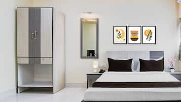 Ein modernes Schlafzimmer mit einem großen Bett, einem Kleiderschrank, einem Nachttisch mit Lampe und drei gerahmten Kunstwerken an der Wand.