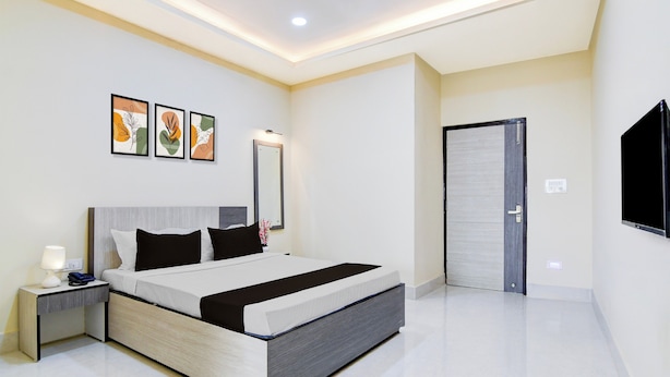 Un dormitorio moderno con cama, mesita de noche, lámpara y una obra de arte en la pared.