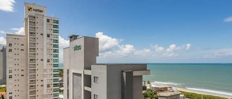 A hotel with a view of the ocean, a tall building with a 'Vettel' sign, and a modern building with 'glo' branding.