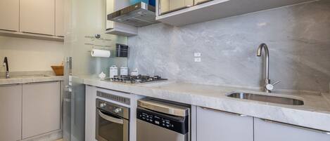 A modern kitchen with stainless steel appliances, a marble countertop, and a built-in dishwasher.