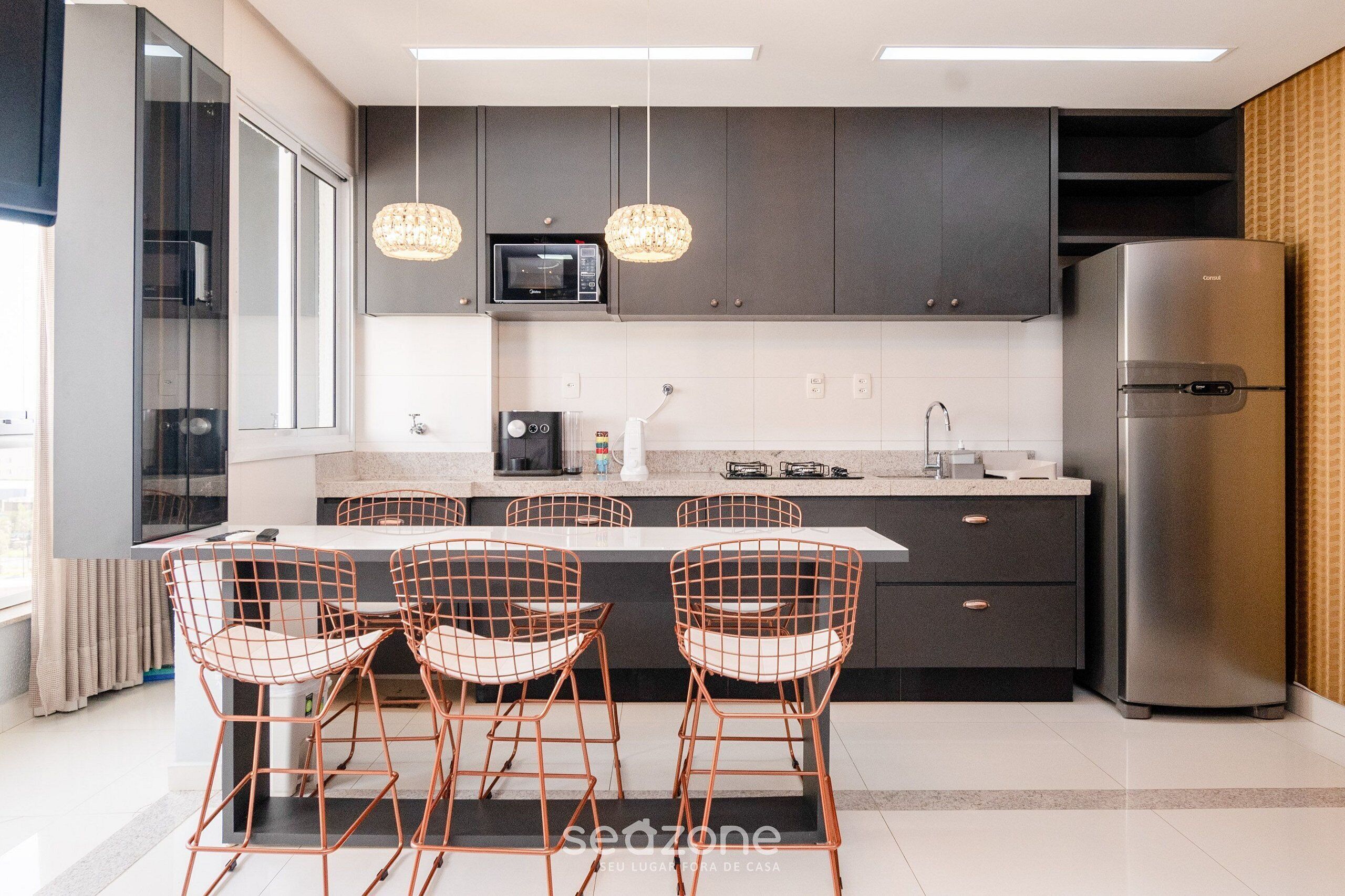 A modern kitchen with a central island, stainless steel appliances, and pendant lighting.