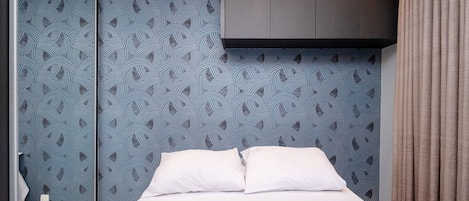 Una habitación de hotel con una cama, un armario y un espejo.