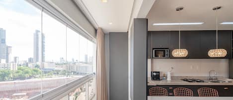 A modern kitchen with a city view, large windows, and contemporary lighting fixtures.