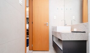 Un bany modern amb una porta de fusta, un lavabo blanc i un mirall a la part superior.