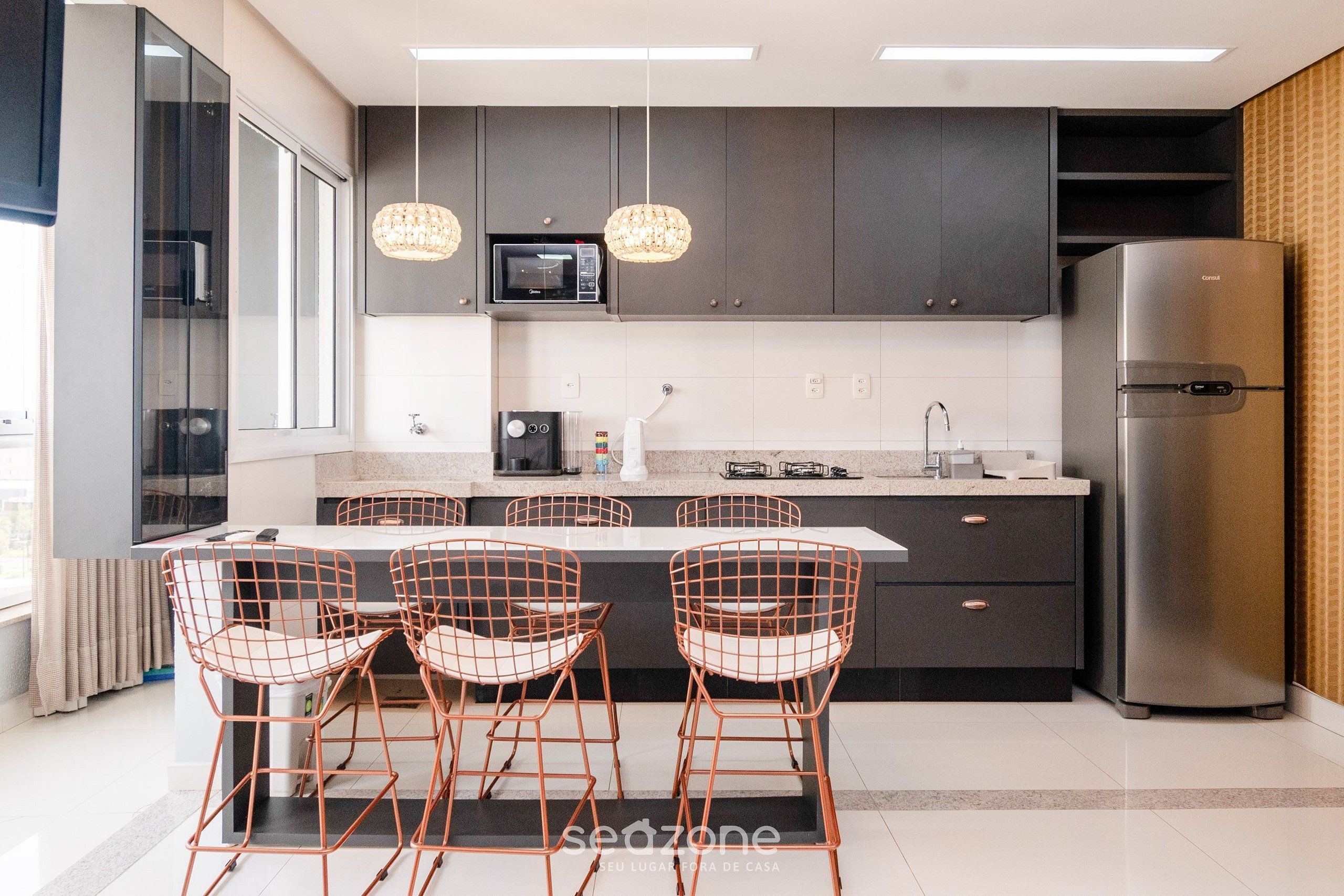 A modern kitchen with a central island, stainless steel appliances, and pendant lighting.