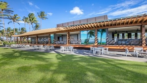 A modern building with outdoor seating and a view of palm trees. - 1BR Plus at Maui Bay Villas, Hilton Grand Vacations Club in Sunny Kihei (Kihei)