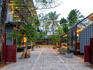 A modern building with a covered outdoor area, stone flooring, and potted plants. - BlackRoots Unawatuna (Galle)